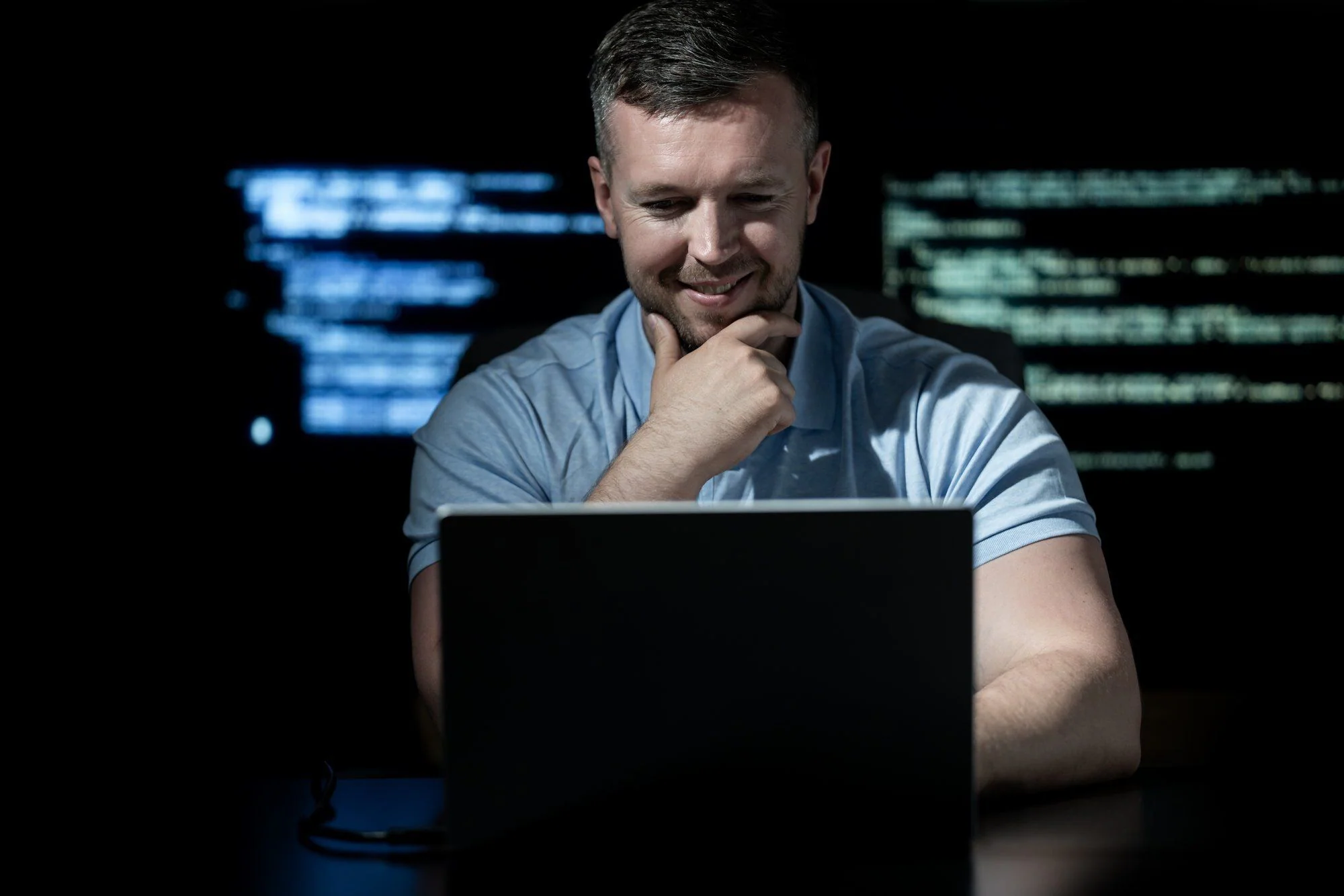 Programmerare arbetar med kod och cybersäkerhetsövervakning på en bärbar dator