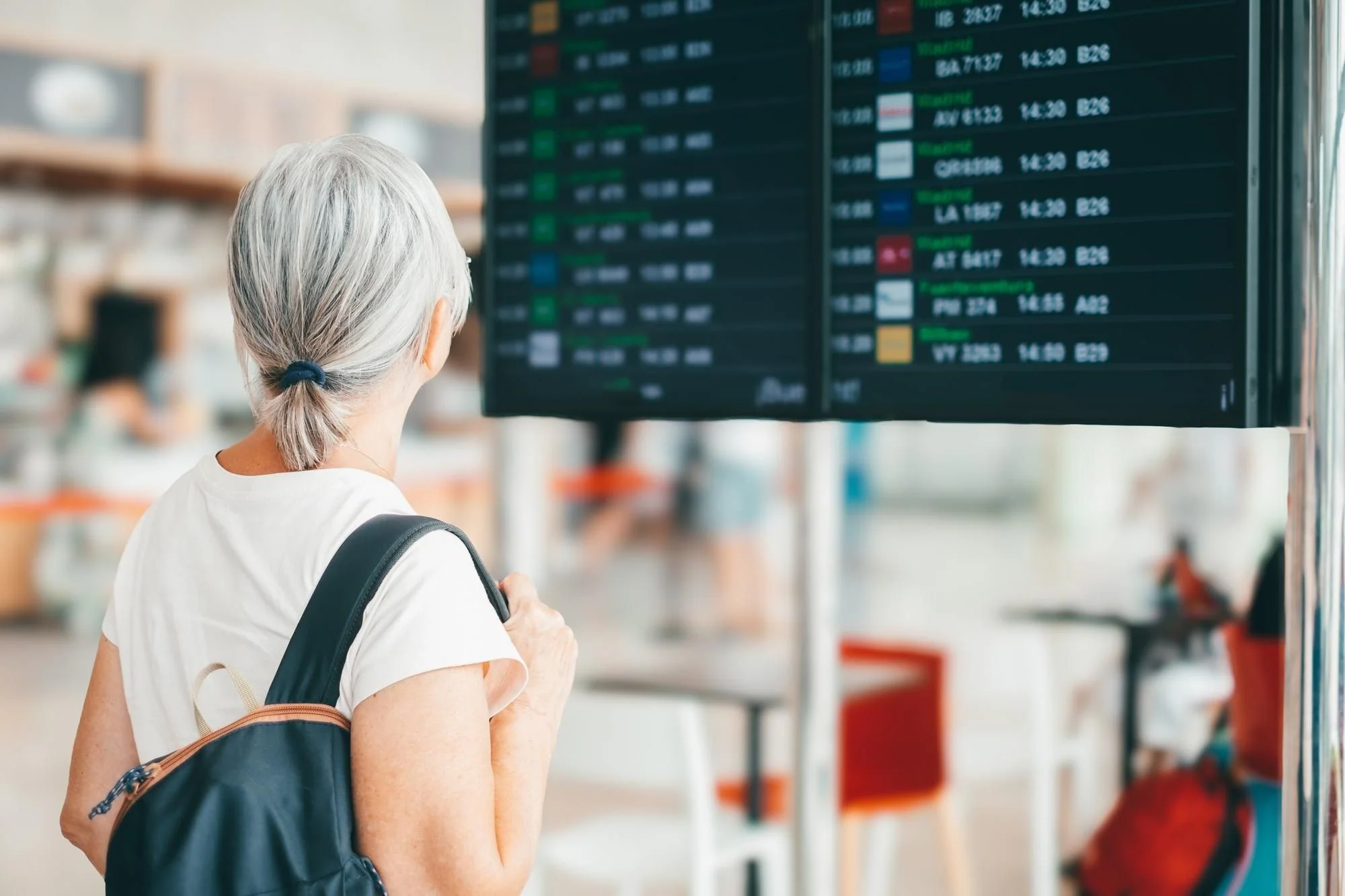 Resenär jämför flygavgångar på flygplatsens informationstavla inför val av flygbolag