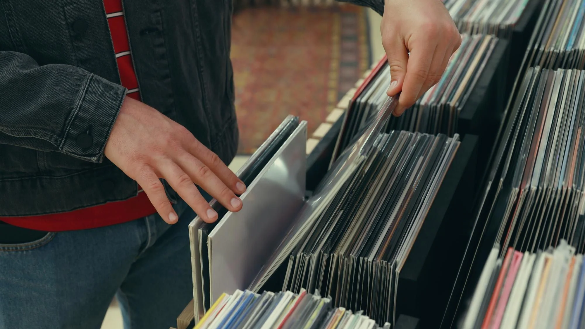 Person bläddrar bland vinylskivor i butik för att jämföra utgåvor och skick
