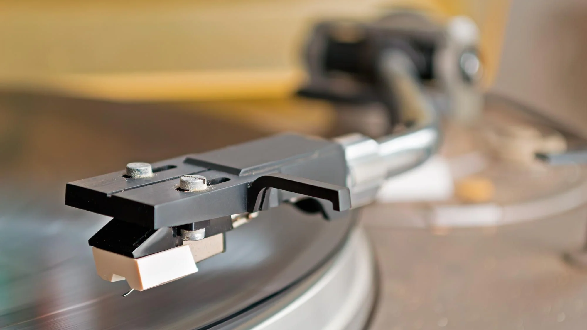 Närbild av skivspelarnål och tonarm över en roterande vinylskiva